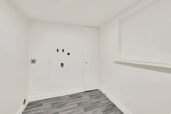 Wood-finish flooring, white walls, and a window with a sill