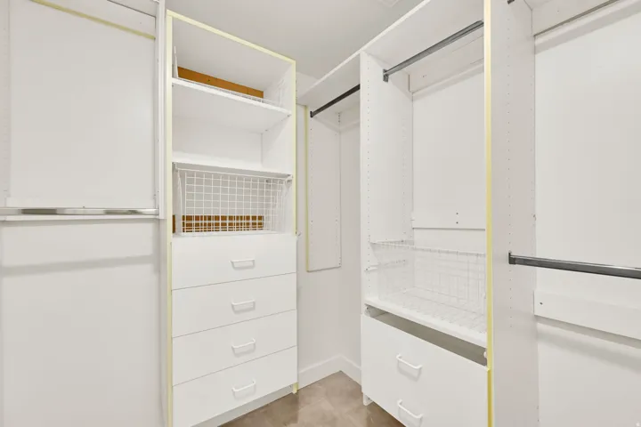 Built-in closet organization system featuring white shelving, integrated drawers, and metal hanging rods