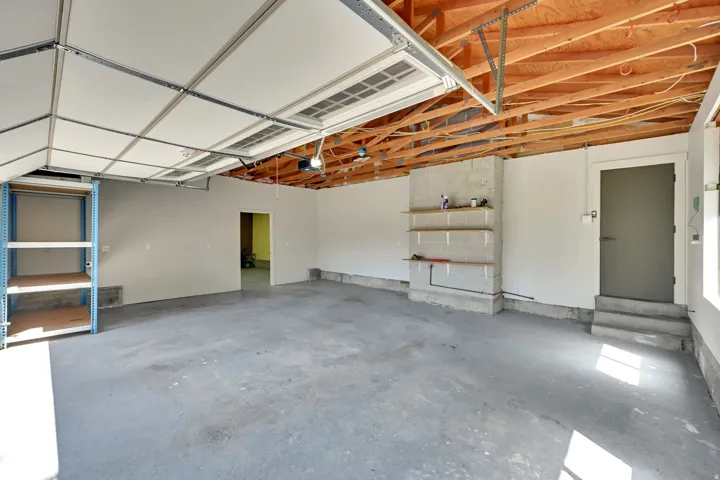 Spacious garage with exposed wood beam ceiling and concrete flooring