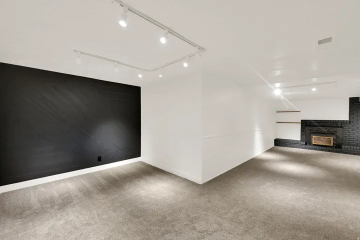 Track lighting system, textured accent wall, black brick fireplace surround, integrated fireplace insert, and built-in shelving