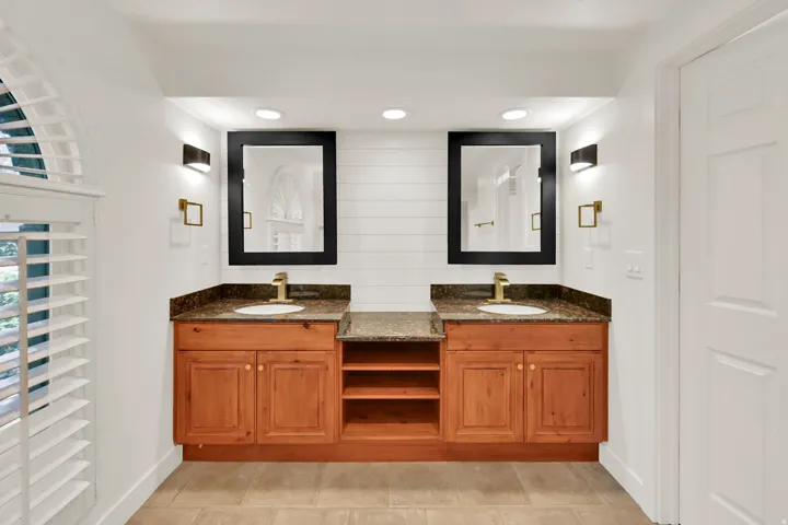 Dual vanity with wood cabinetry, granite countertops, and under-mount sinks