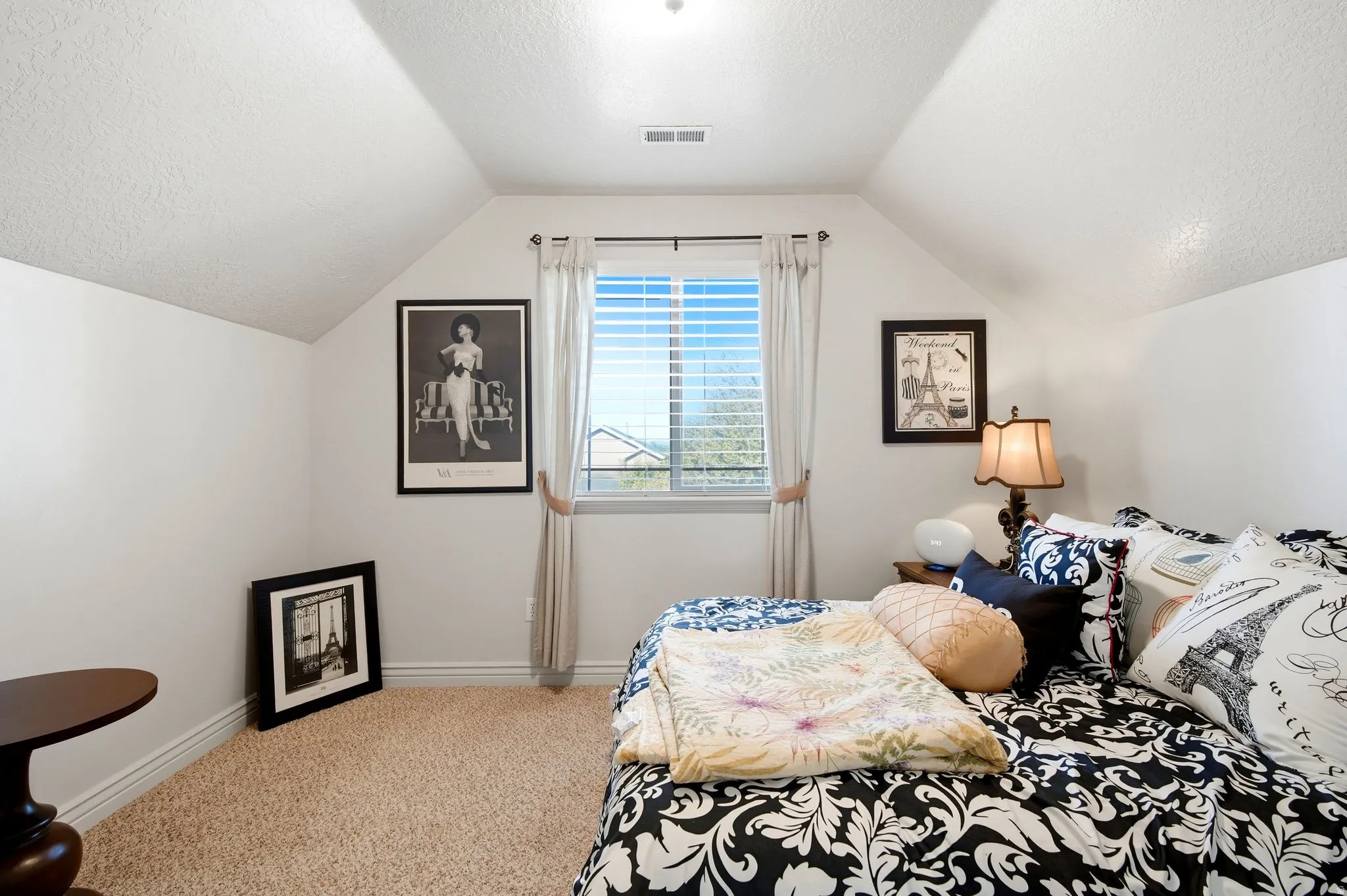 Vaulted ceiling featuring a central light fixture, window with blinds and curtains, and neutral-toned carpeting