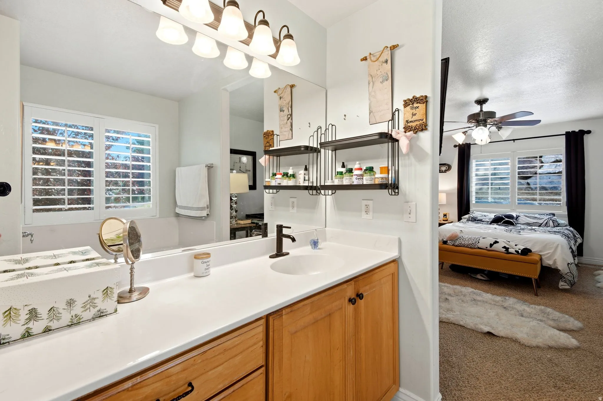 Bathroom vanity with an integrated sink, broad mirror, and warm wood-finish cabinetry