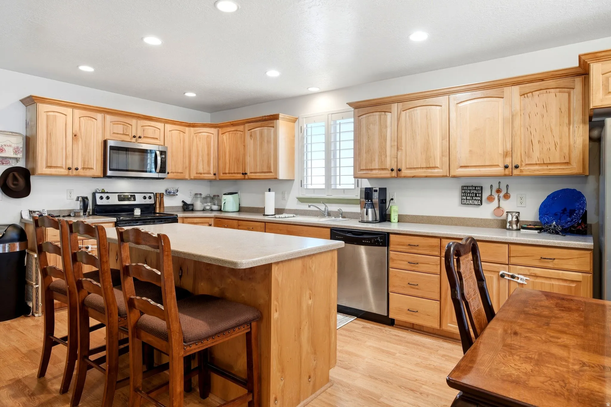 Kitchen featuring wood-finish cabinetry, stainless steel appliances, a center island with counter seating, and recessed lighting