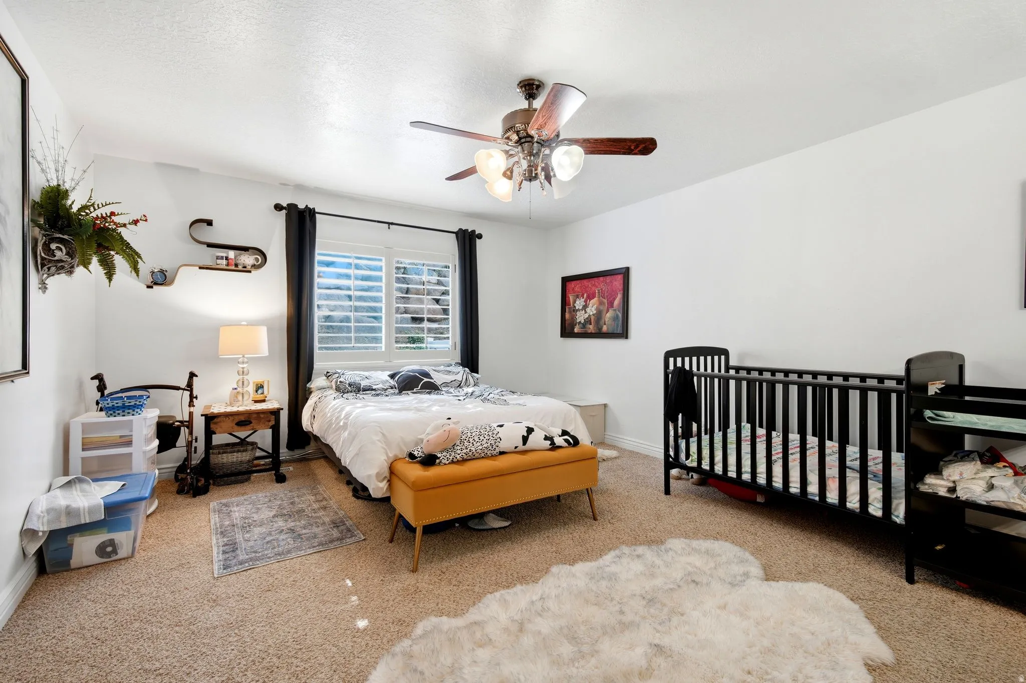 Carpeted room featuring a window with plantation shutters, a ceiling fan with integrated lighting, and white wall finishes