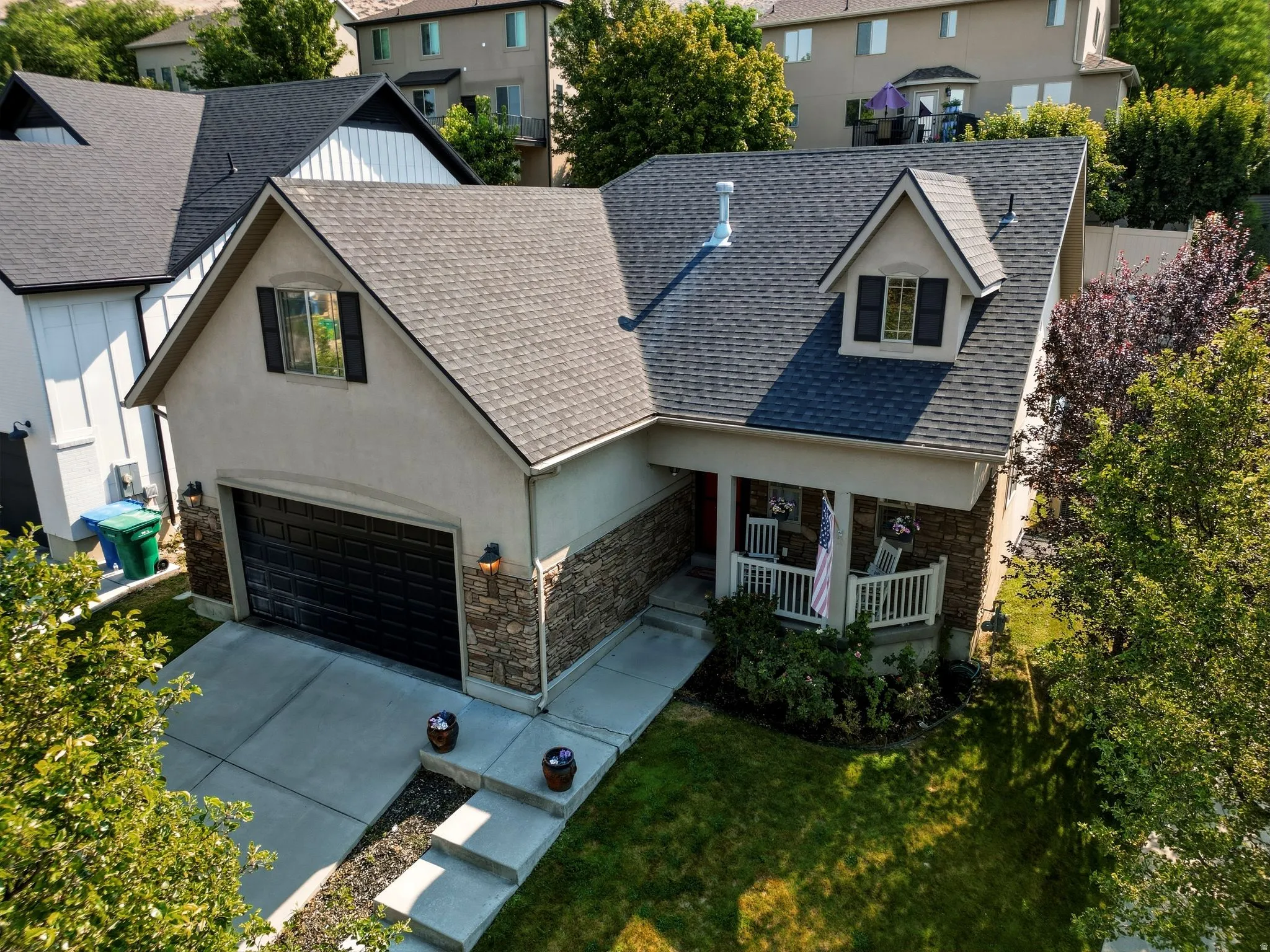Two-story residence featuring a covered front porch, dormer window, and an attached two-car garage