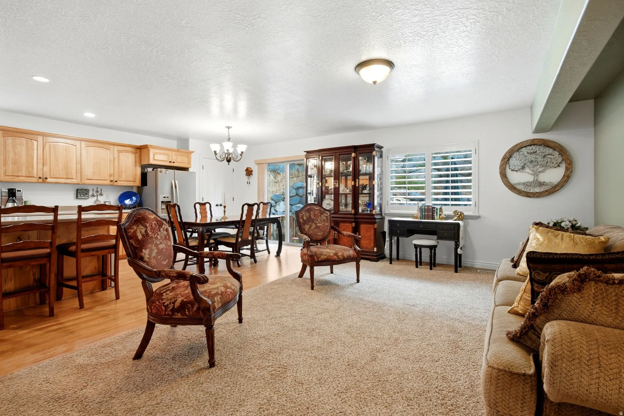 Kitchen with wood cabinetry, dining area with chandelier, sliding glass door, and window with plantation shutters
