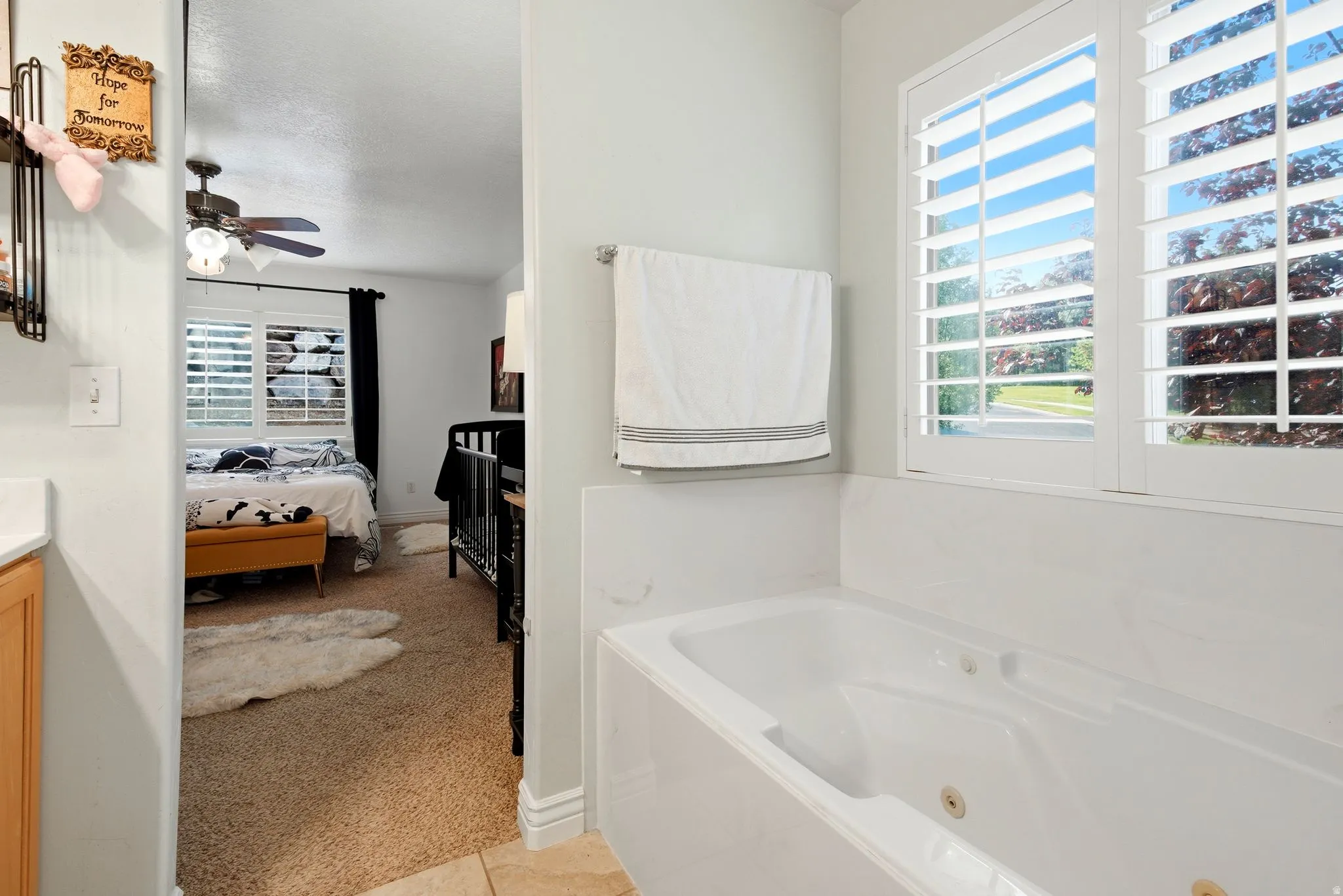 Built-in jetted tub with white plantation shutters and natural wood cabinetry