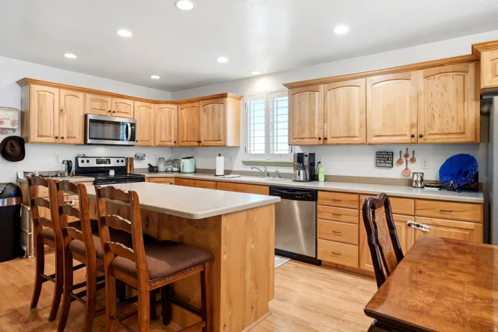 Kitchen featuring wood-finish cabinetry, stainless steel appliances, a center island with counter seating, and recessed lighting