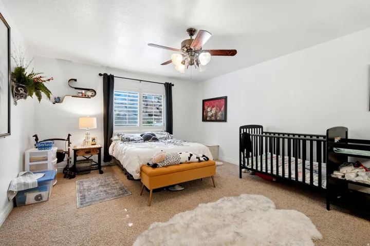 Carpeted room featuring a window with plantation shutters, a ceiling fan with integrated lighting, and white wall finishes