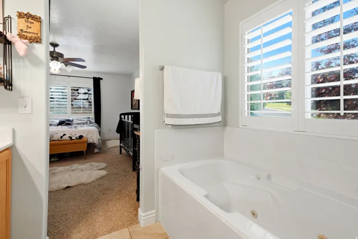 Built-in jetted tub with white plantation shutters and natural wood cabinetry