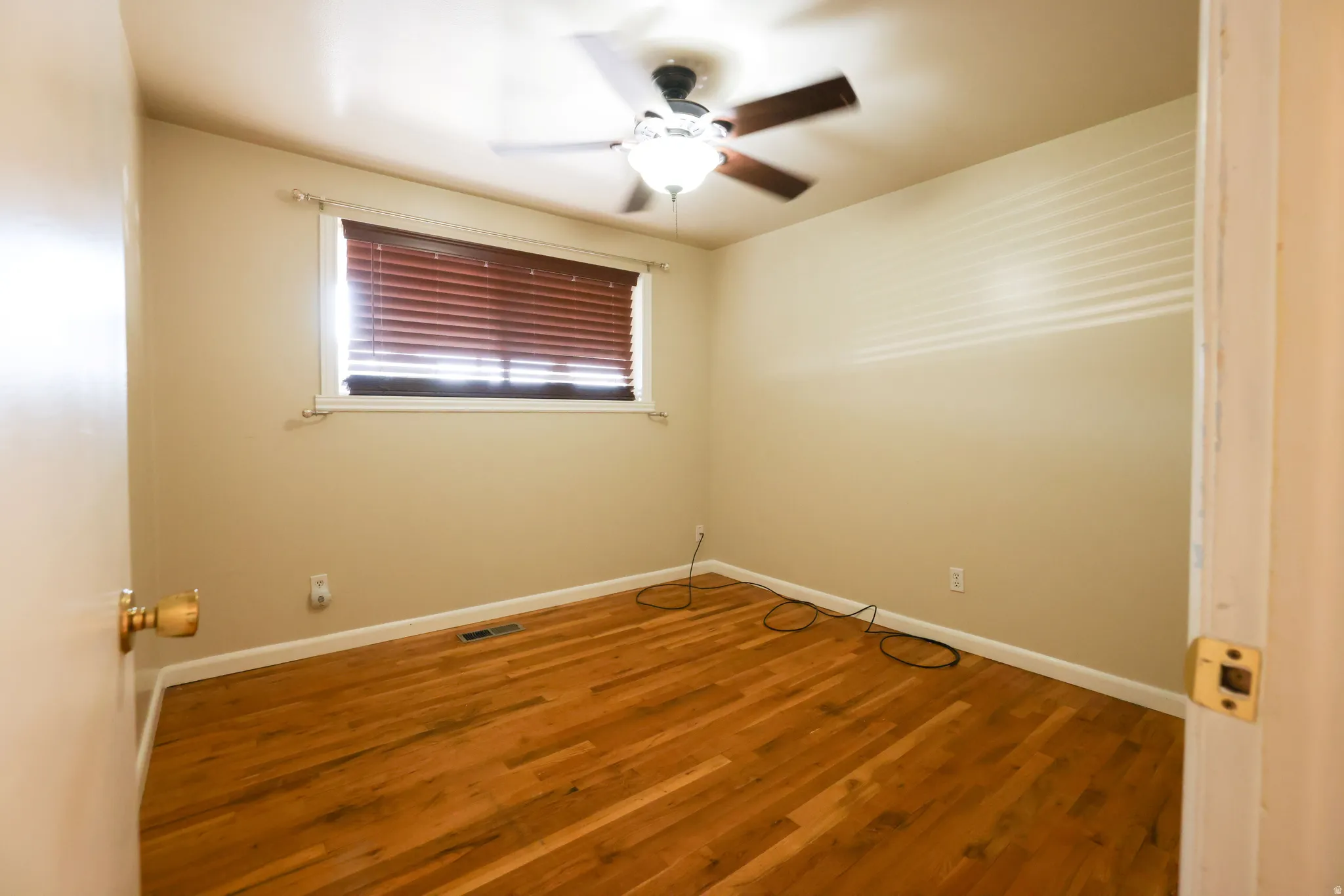 Warm wood flooring, neutral wall tones, and a ceiling fan