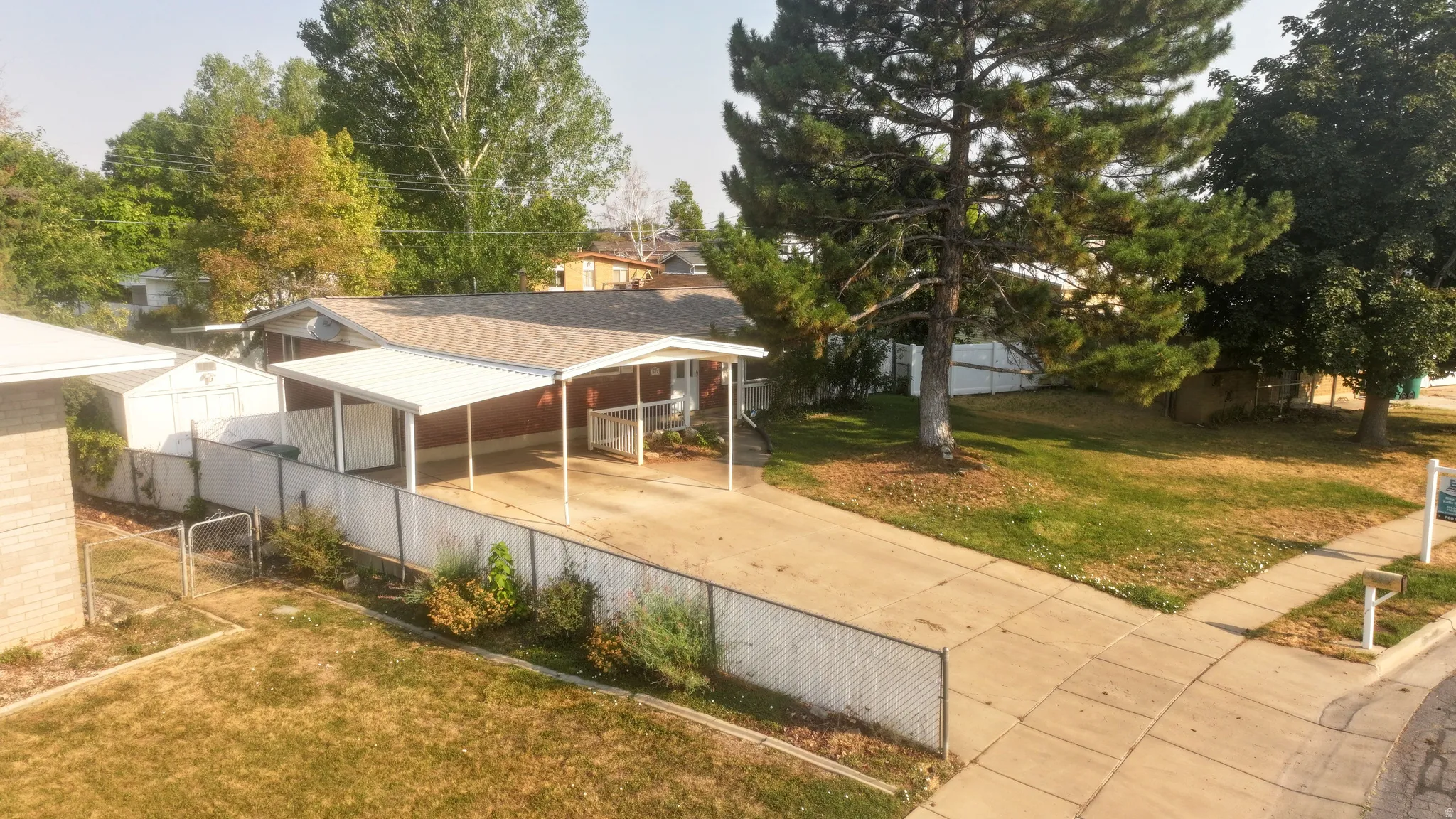 Property featuring a paved driveway, a covered carport, and a separate storage shed