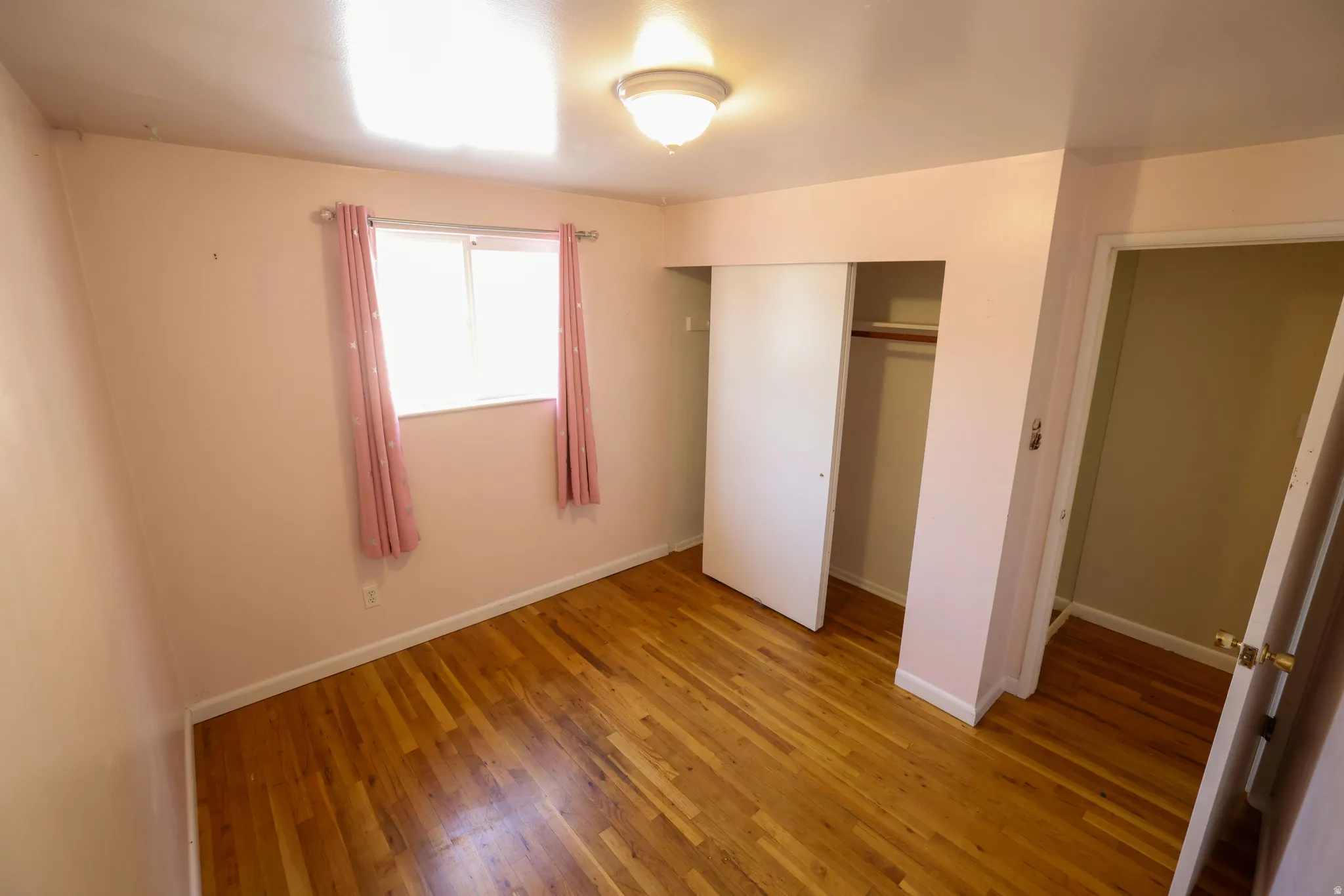 Hardwood flooring, recessed window, built-in closet with sliding doors, flush mount ceiling light fixture