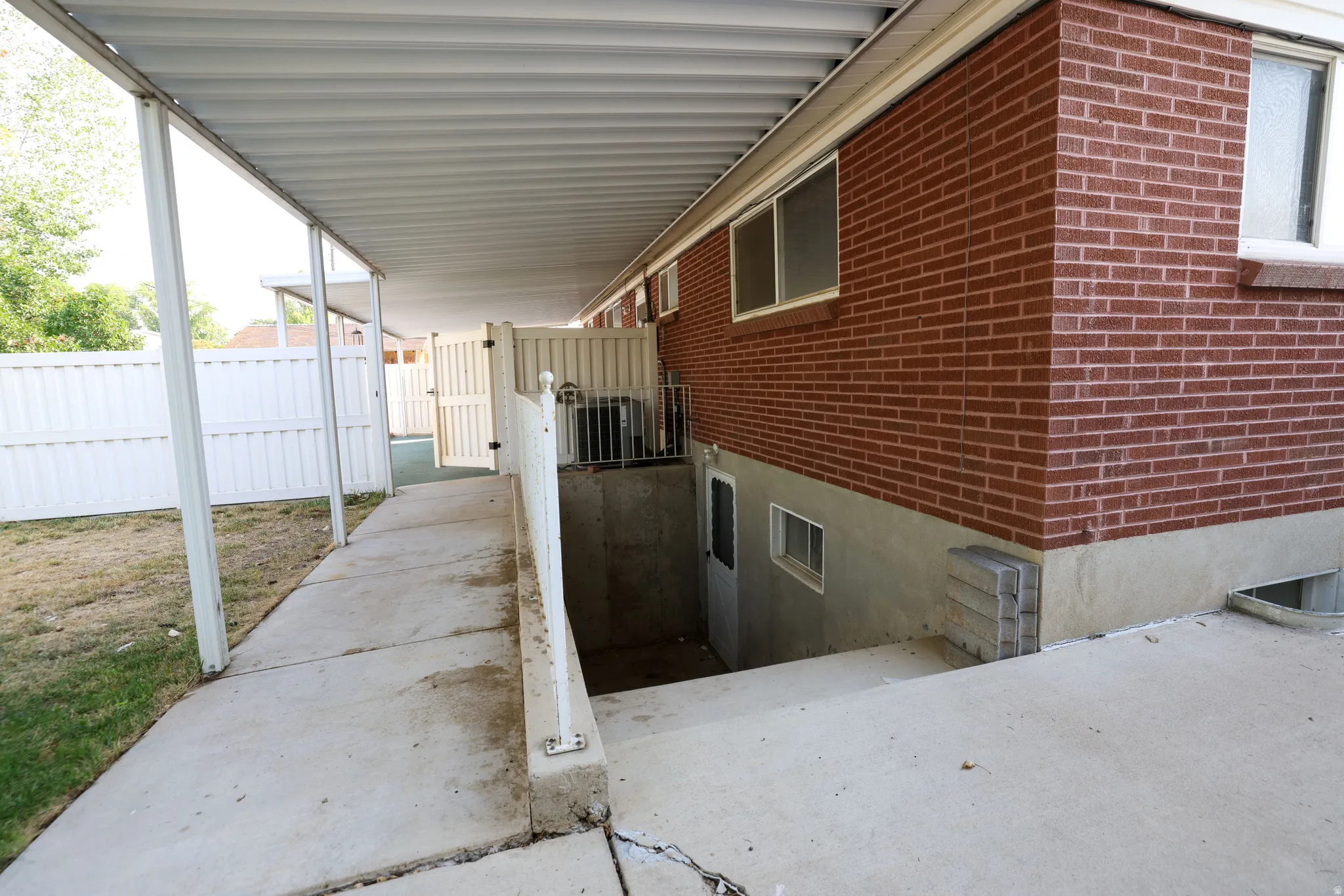 Covered walkway with a concrete pathway and a white privacy fence
