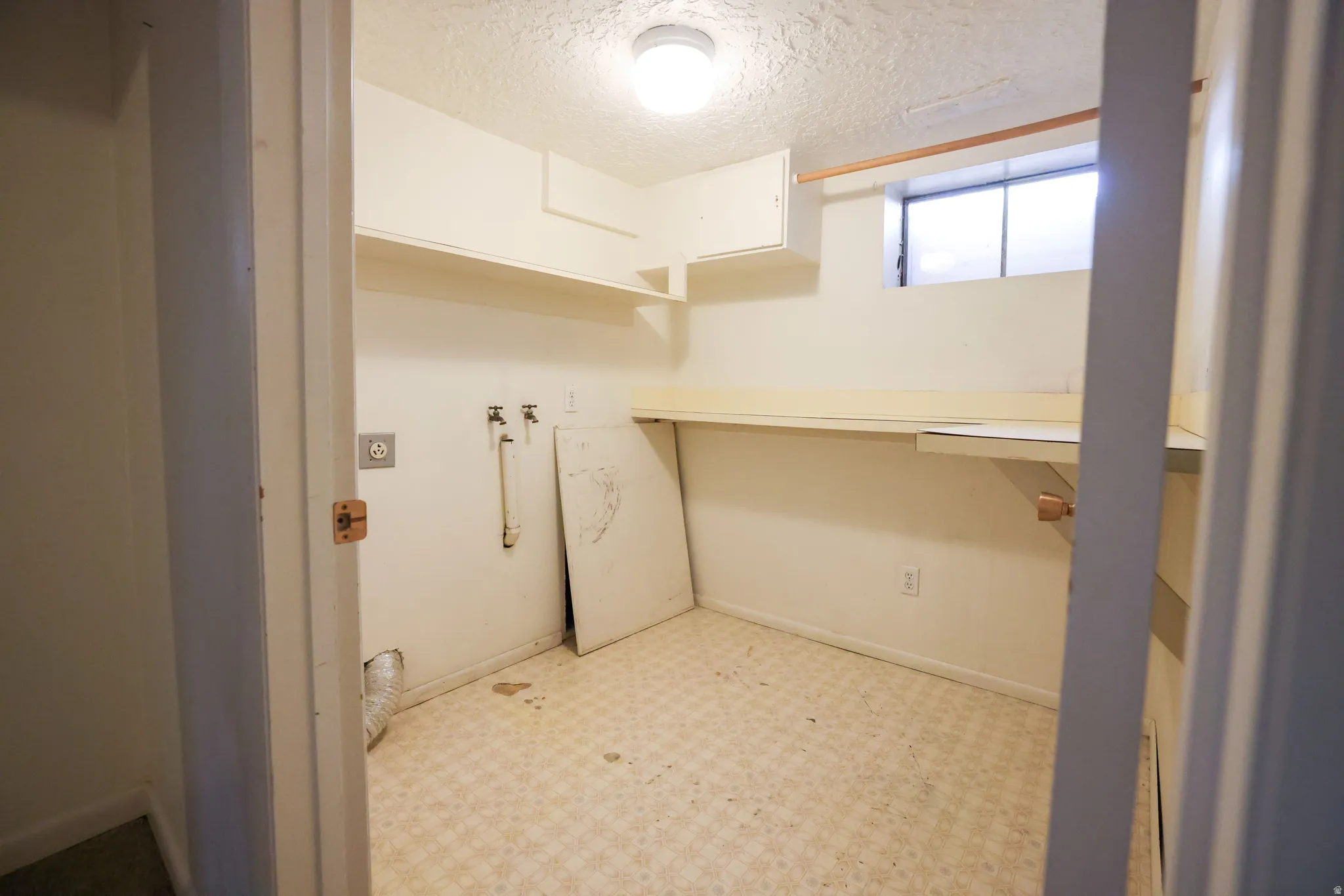 Laundry room featuring a window, built-in shelving, and a built-in countertop