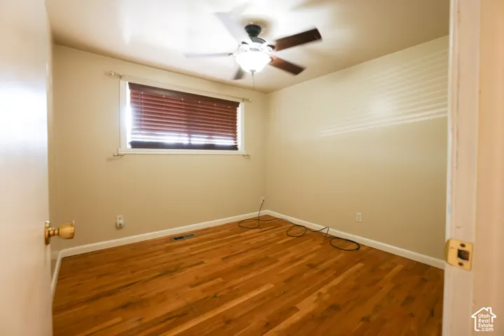 Warm wood flooring, neutral wall tones, and a ceiling fan