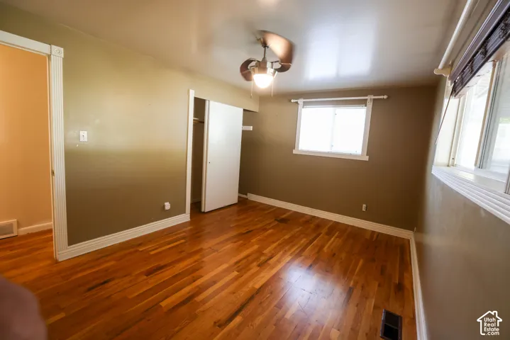 Spacious room featuring rich wood-finish flooring, neutral wall tones, and abundant natural light from multiple windows