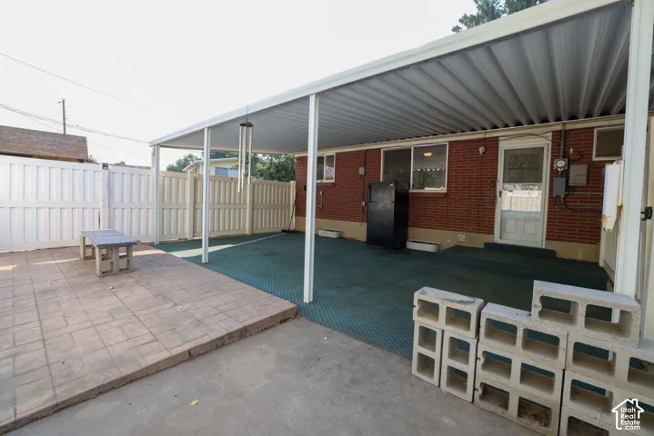 Covered patio with a corrugated metal roof, brick exterior, and a privacy fence