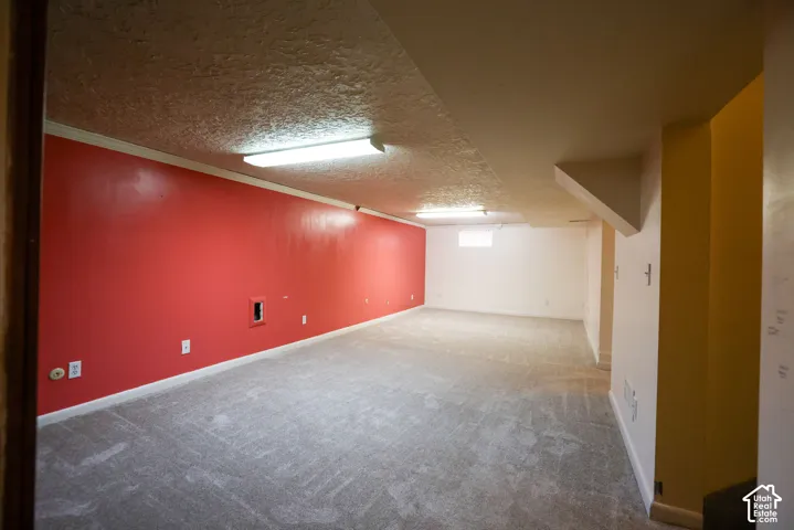 Spacious room featuring carpeting, multiple electrical outlets, overhead fluorescent lighting, and a small window