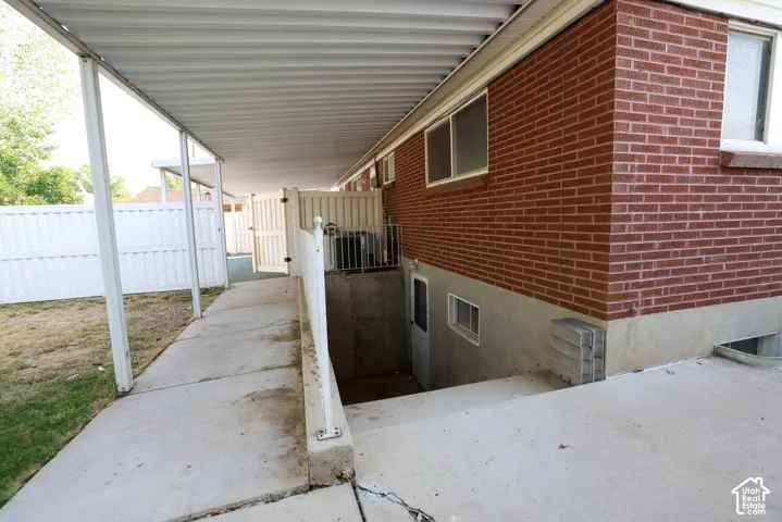 Covered walkway with a concrete pathway and a white privacy fence