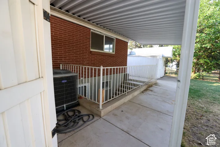 Red brick exterior, concrete patio, white metal railing, corrugated metal patio cover, exterior HVAC unit