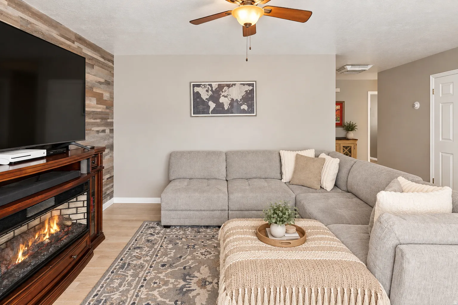 Accent wall featuring wood paneling, wood-finish flooring, ceiling fan, and an electric fireplace with a wood mantel