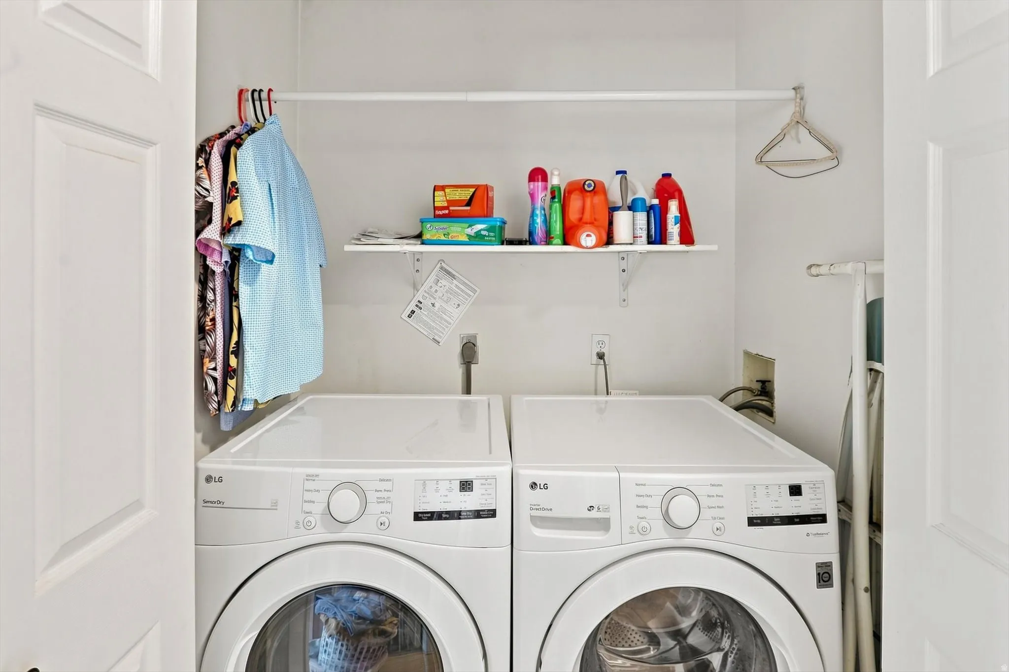 Dedicated laundry area featuring a built-in shelving unit, clothes hanging rod, and white appliances