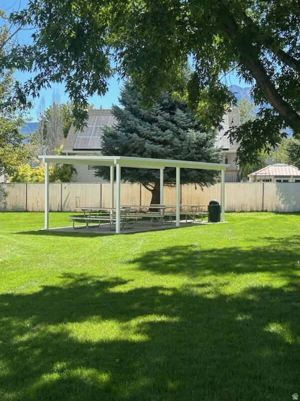 HOA community park expansive green space featuring a covered outdoor structure and mature trees