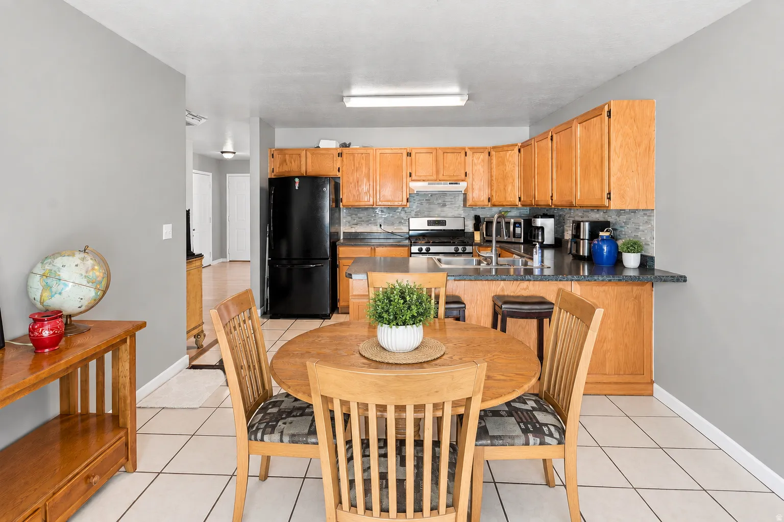 Kitchen with wood-finish cabinetry, dark countertops, a tile backsplash, and stainless steel appliances