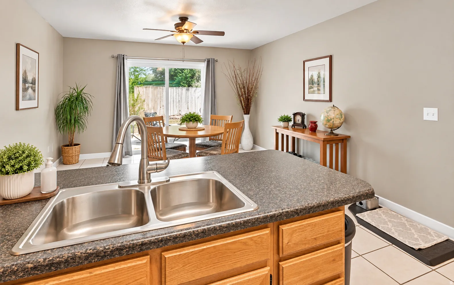 Stainless steel double-basin sink with a gooseneck faucet, light wood-finish cabinetry, and a dark speckled countertop