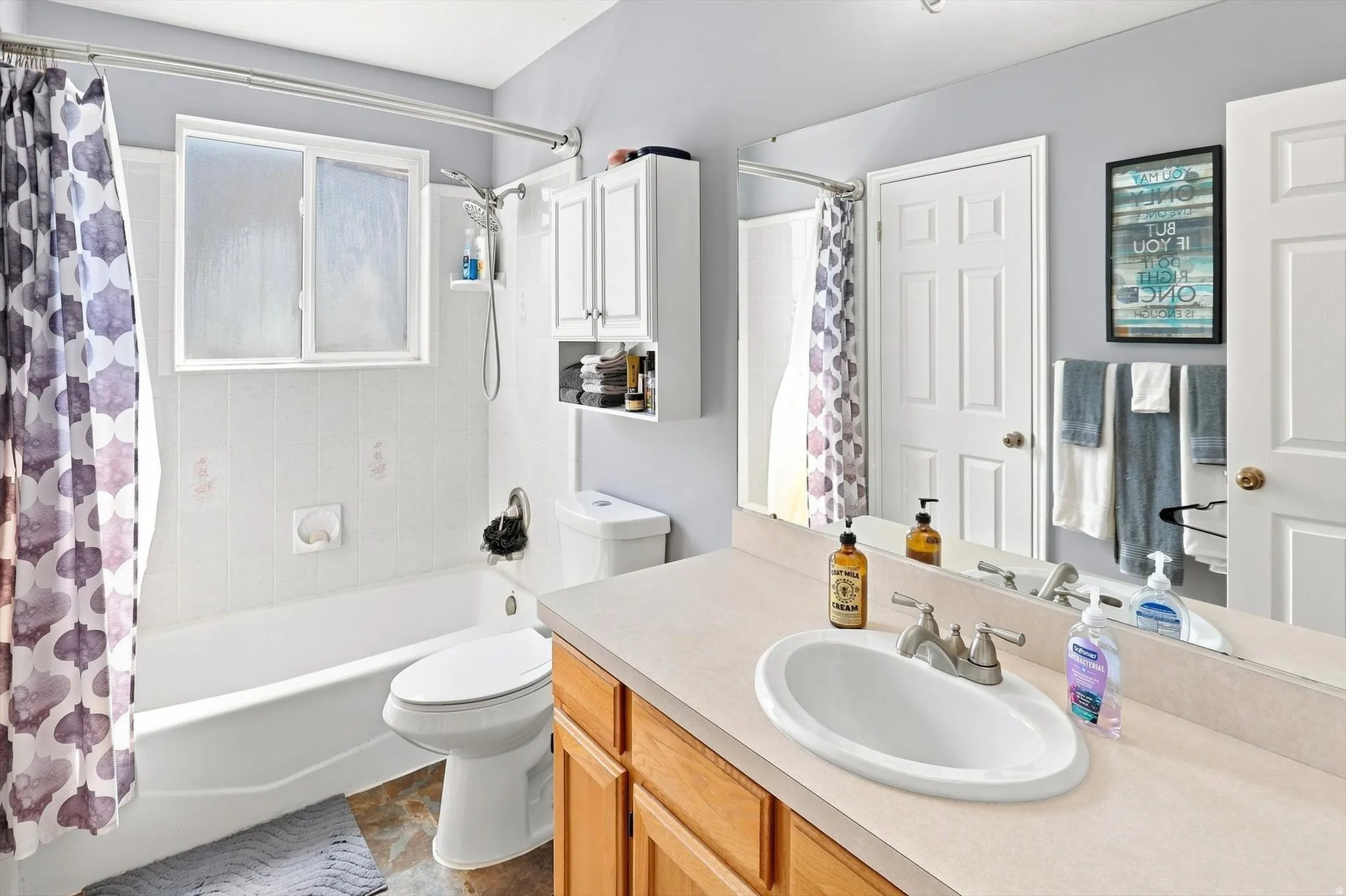 Recessed lighting, wood-finish vanity with an integrated sink, and an expansive wall-mounted mirror