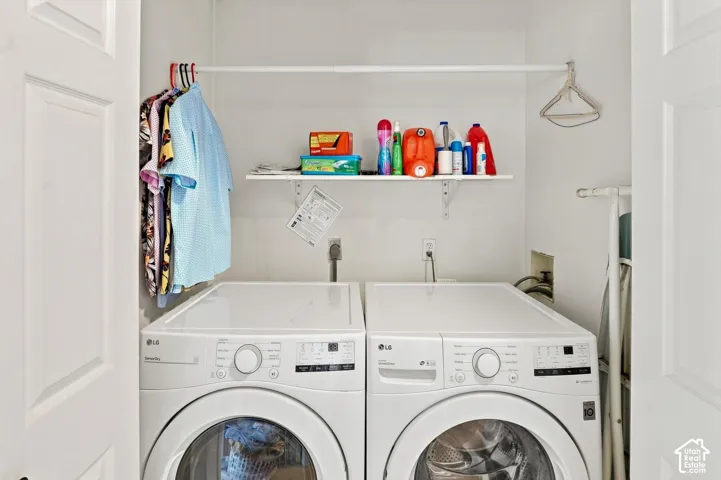 Dedicated laundry area featuring a built-in shelving unit, clothes hanging rod, and white appliances