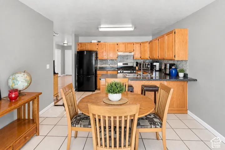 Kitchen with wood-finish cabinetry, dark countertops, a tile backsplash, and stainless steel appliances