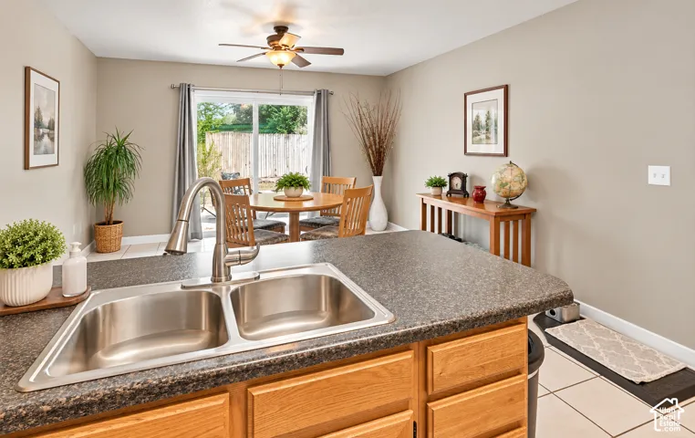 Stainless steel double-basin sink with a gooseneck faucet, light wood-finish cabinetry, and a dark speckled countertop