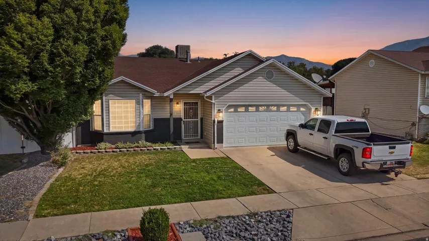 Single-story residence featuring light-colored siding, a two-car garage, and a concrete driveway