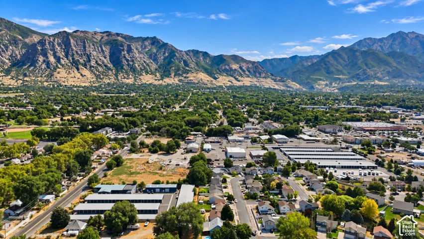Expansive mountain backdrop with a wide urban area featuring numerous residential properties, commercial structures, and mature trees