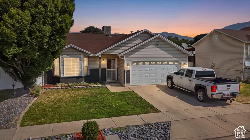 Single-story residence featuring light-colored siding, a two-car garage, and a concrete driveway