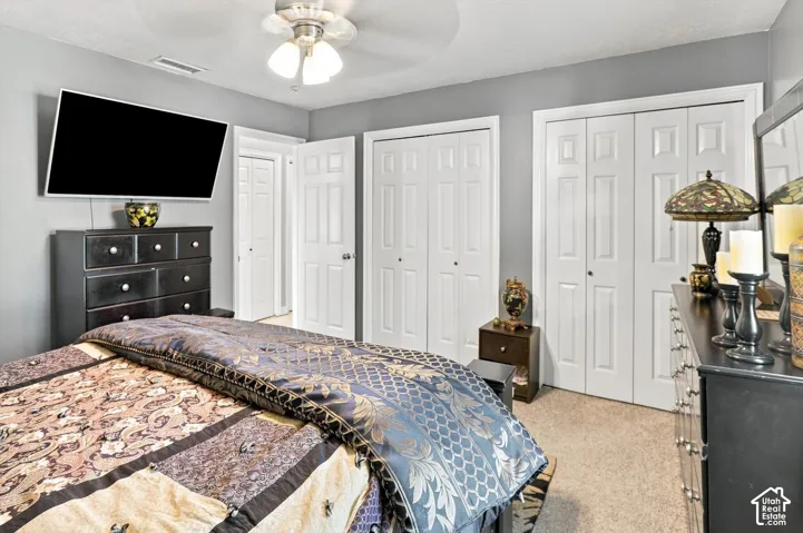 Neutral wall color, ceiling fan with integrated lighting, multiple paneled closet doors, carpeted flooring