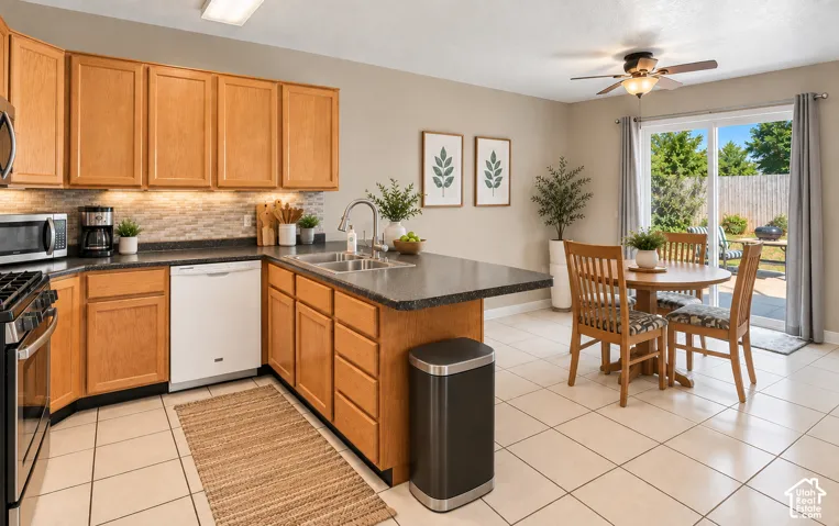 Kitchen featuring wood cabinetry, stone-look countertops, a tile backsplash, and stainless steel appliances