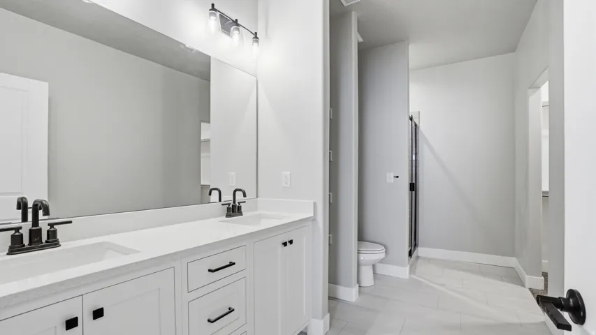Dual vanity with white cabinetry, integrated sinks, and black hardware