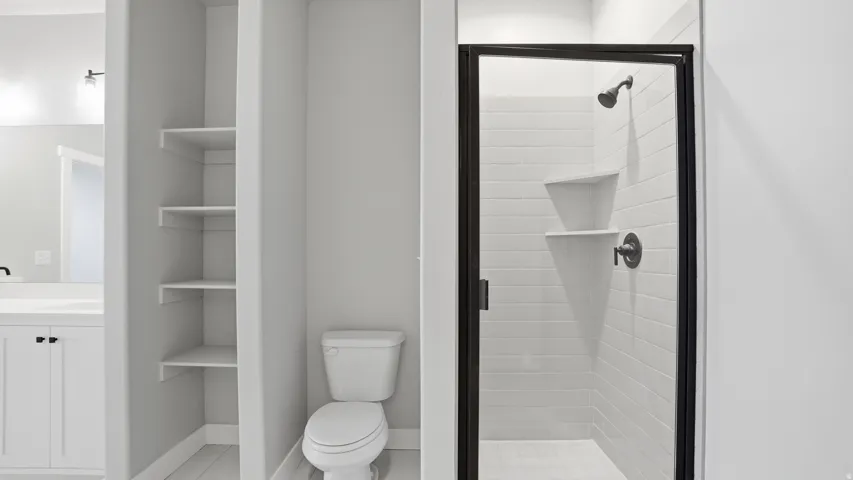 Bathroom featuring a glass-enclosed shower with subway tile surround and integrated shelving
