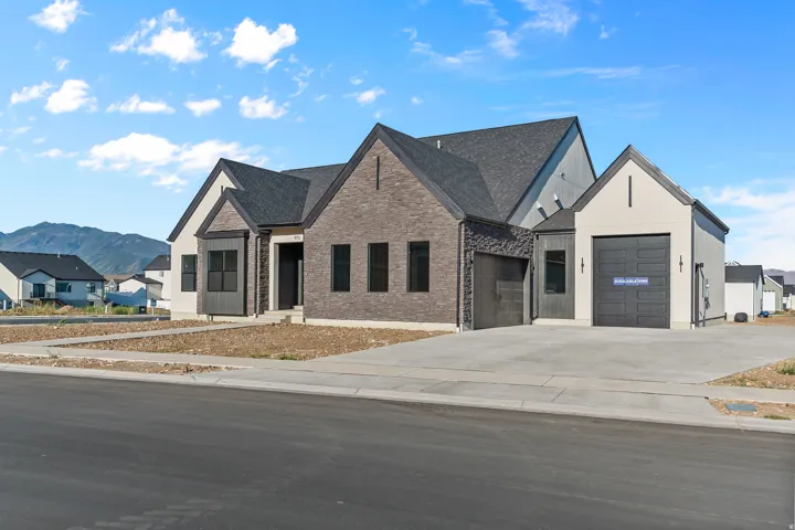 Contemporary exterior featuring a combination of brick and siding finishes, dark framed windows, a multi-car driveway, and a prominent dark roofline