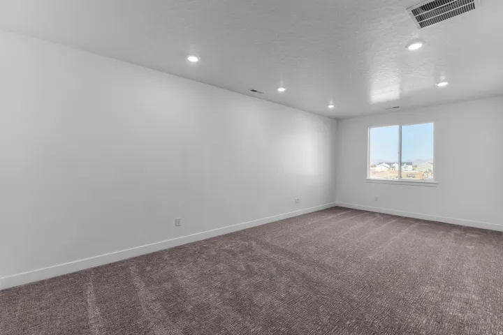 Spacious room with recessed lighting, neutral textured carpeting, and a large window with white trim