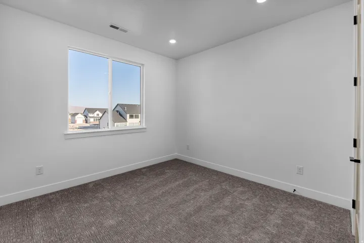 Neutral-toned walls, recessed lighting, and textured carpet flooring