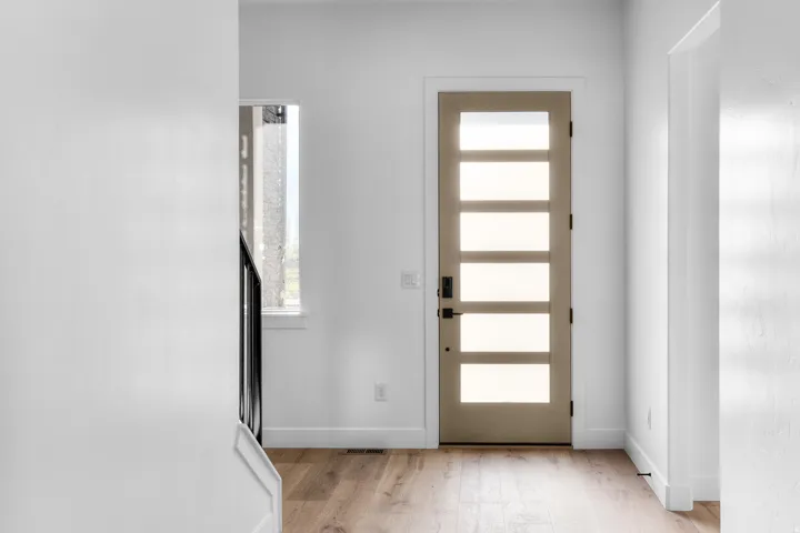 Modern entry door with five frosted glass panels, wood-finish flooring, and crisp white walls