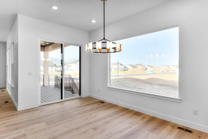 Wood-finish flooring, recessed ceiling lights, contemporary chandelier, large picture window, and sliding glass door to a covered deck