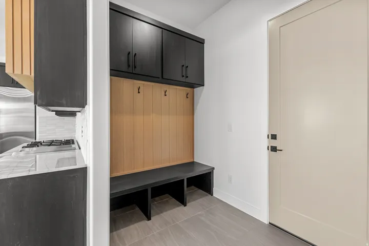 Built-in cabinetry with dark finishes, light wood-finish paneling, and a coordinated bench