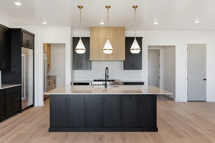 Kitchen featuring a large island with a light-toned countertop, dark cabinetry, stainless steel appliances, and wood-finish flooring