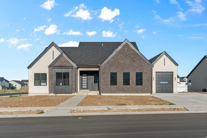 Modern exterior featuring a dark asphalt shingle roof, light-colored stucco, and dark brick facade